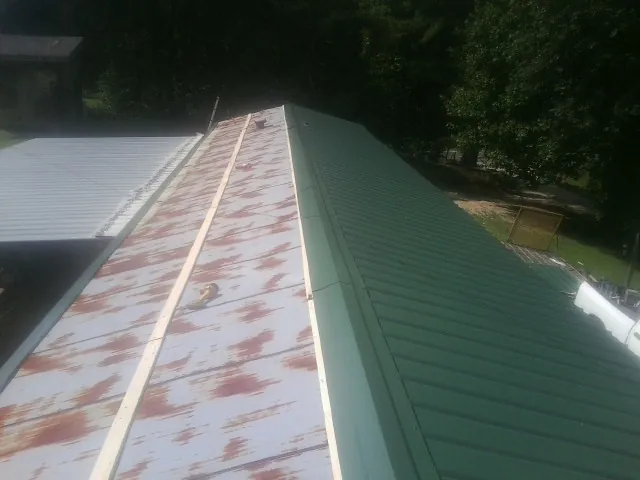 Old rusted panels beside newly installed green metal roofing — Wind Damage Roof Repair by Roofing Brothers in Steinhatchee