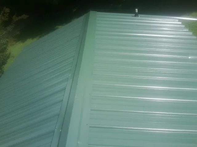 New green metal panels meeting at the ridge of a roof — Flat Roof Repair work by our crew in Steinhatchee