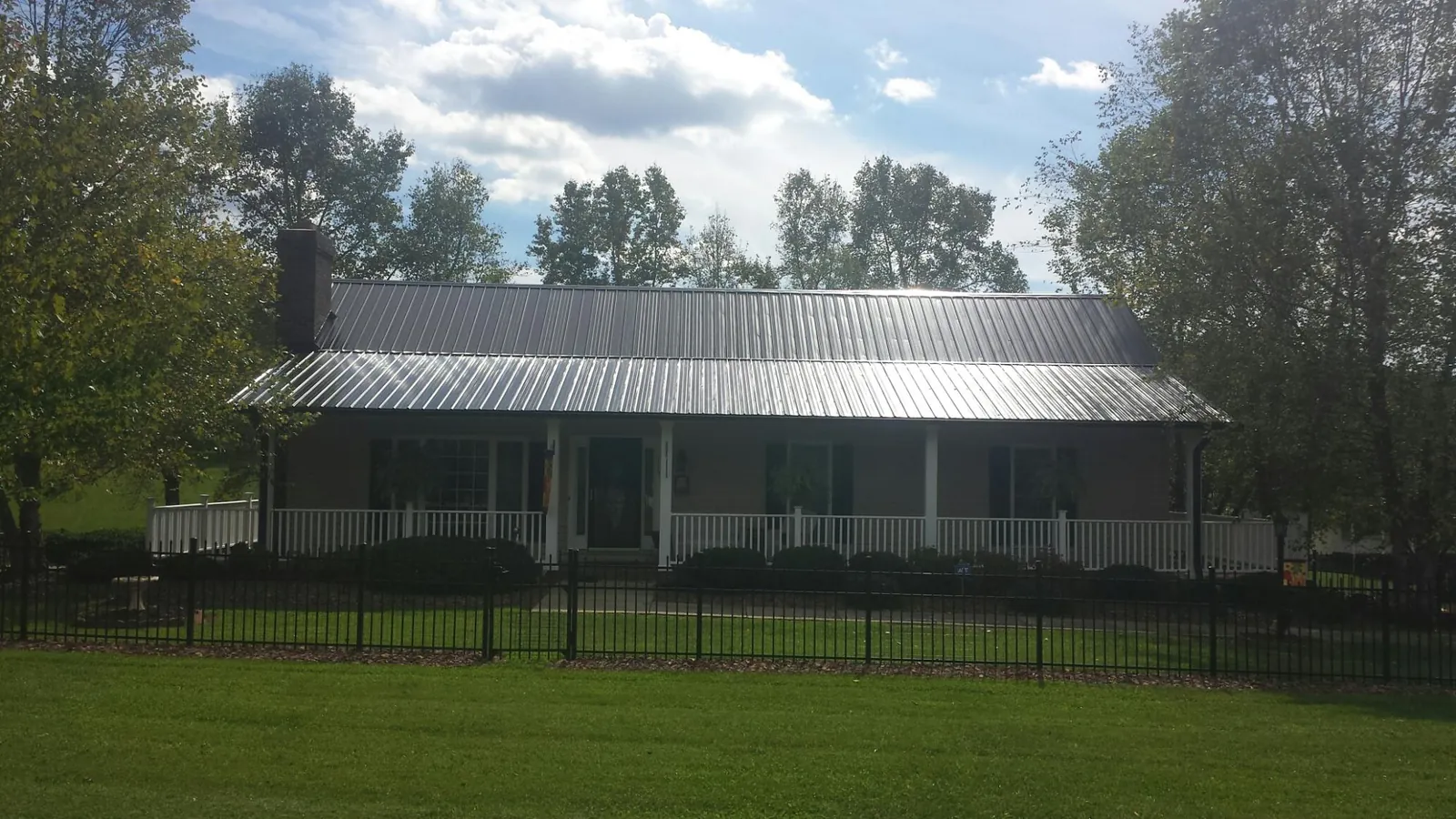 Gray metal roof on a brick ranch with a full width front porch — Gutter Guard Installation work by our crew in Steinhatchee